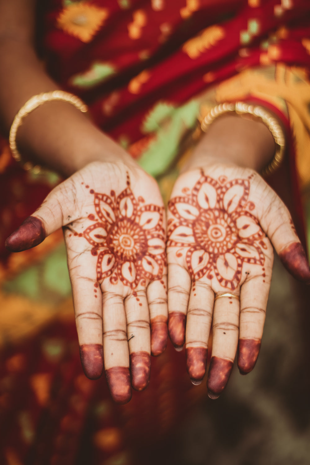 an indian woman in robes presents henna-painted palms