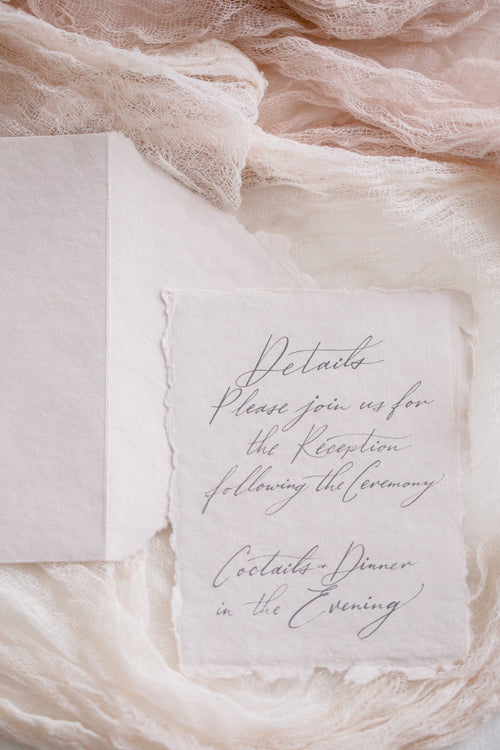 an invite lays surrounded by soft pink fabric