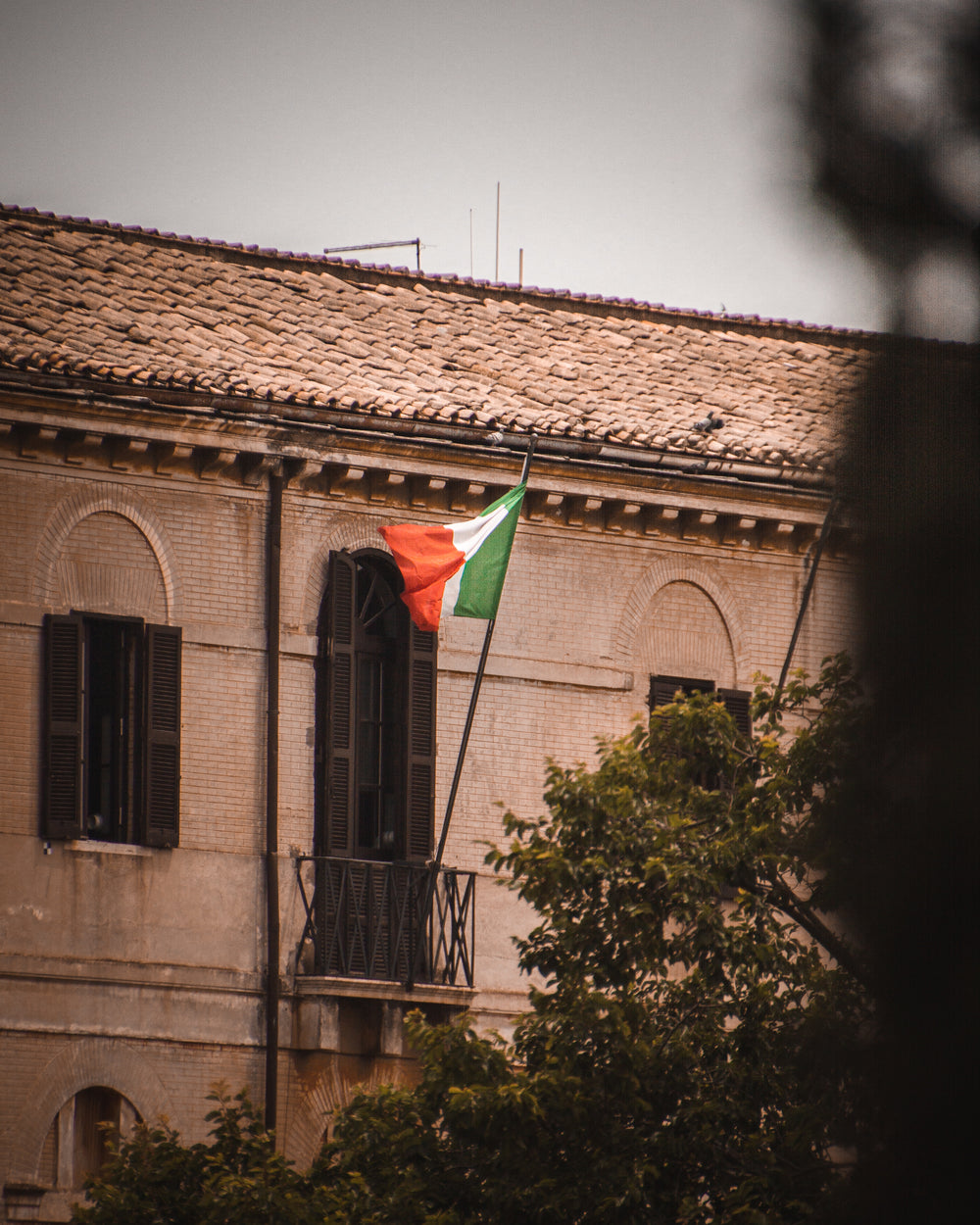 an italian flag billows from a balcony