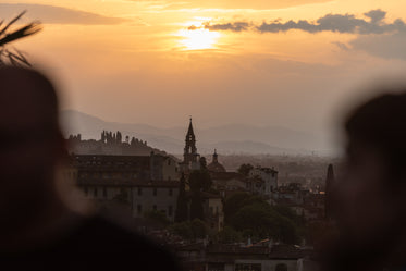 an orange sun hovers in early dawn over a city skyline