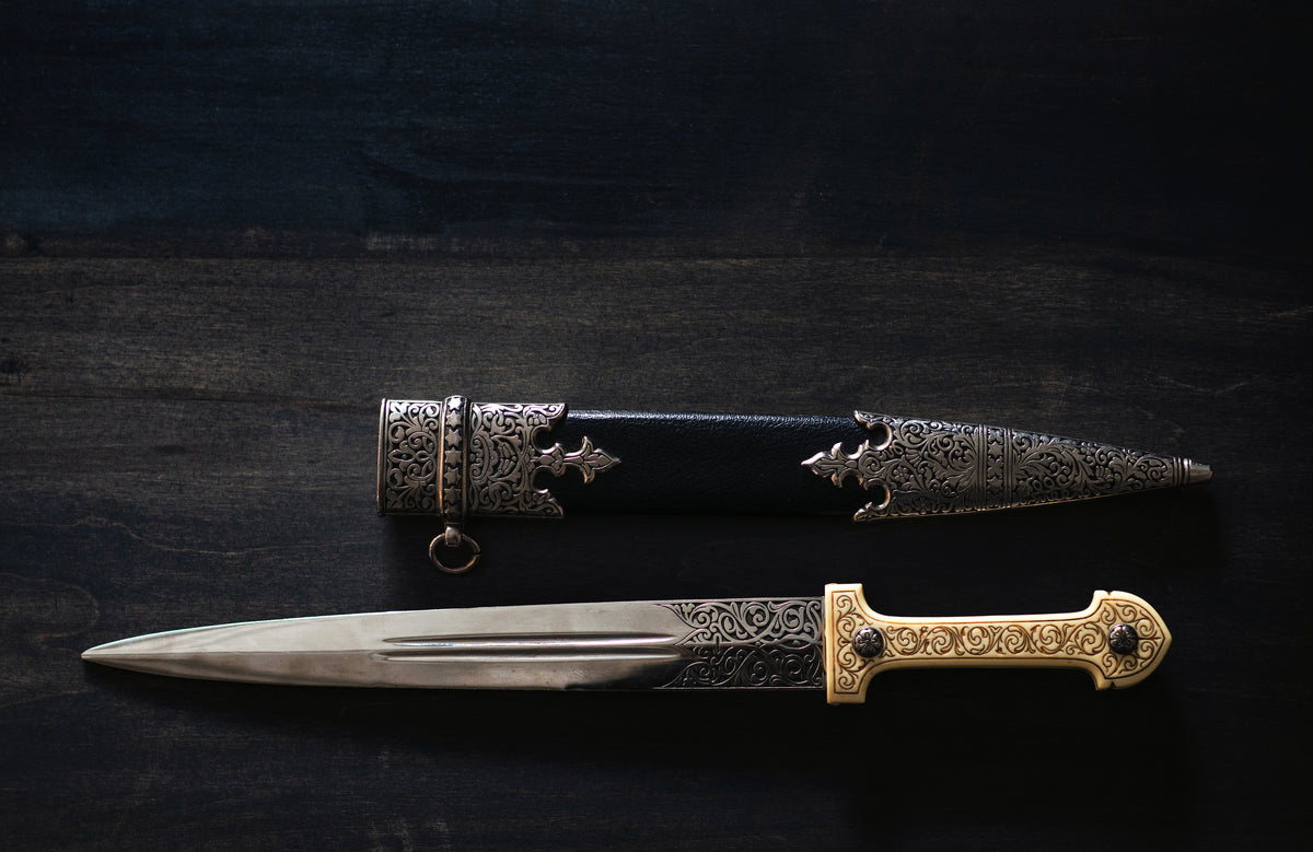 an ornate dagger and sheath on a wooden table