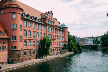 an ornate terracotta building overlooks a river