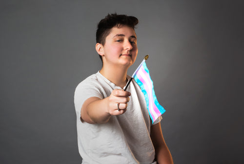 androgynous person holds trans pride flag