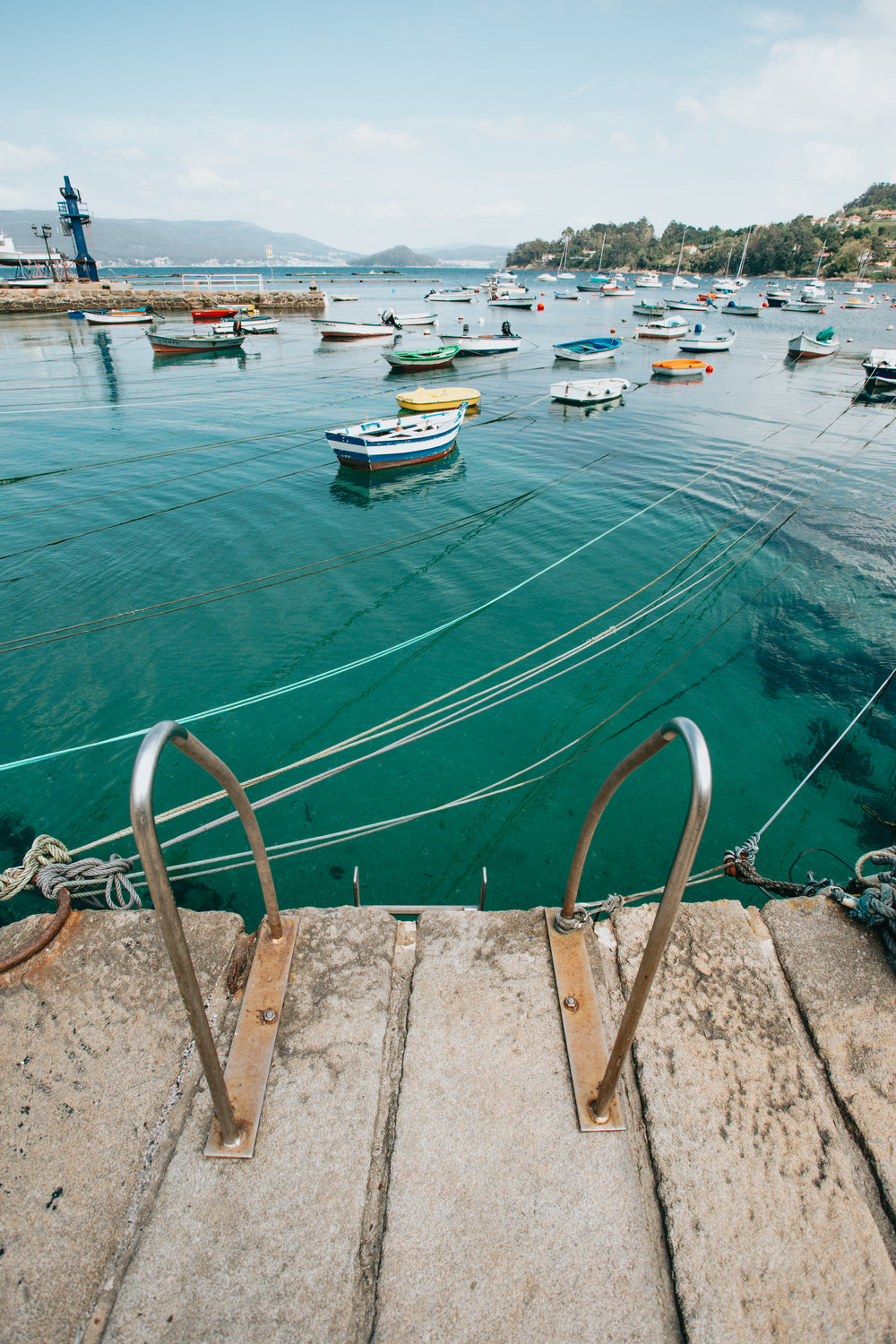 aqua water with boats attached to shore with ropes