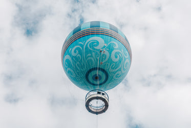 aquamarine hot air balloon rises into puffy clouds