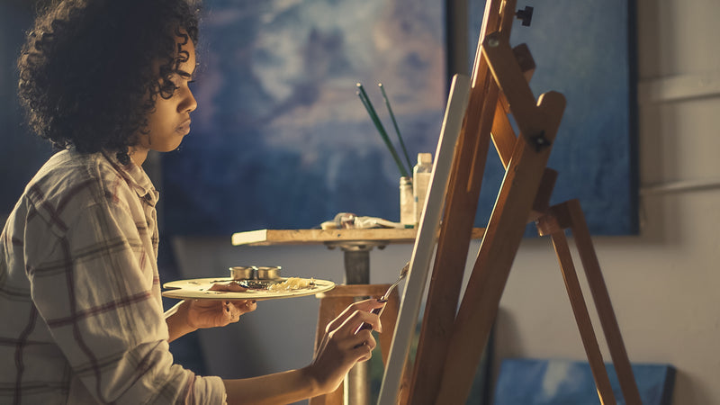 A painter working at an easel in a studio