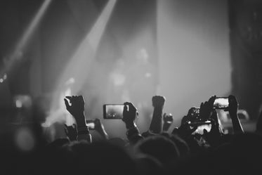 audience members hold up mobile phones filming a concert