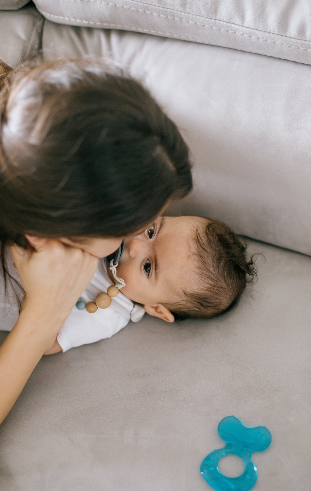 baby and a person lay close on a white couch