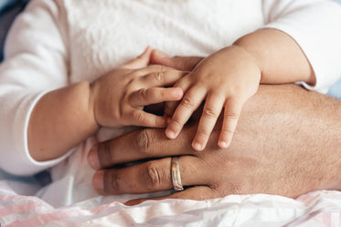 baby girl holding fathers hand