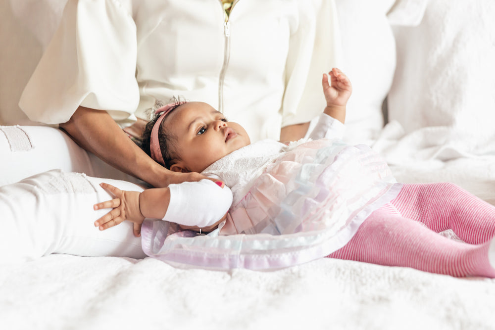 bebê deitada na cama com a mãe