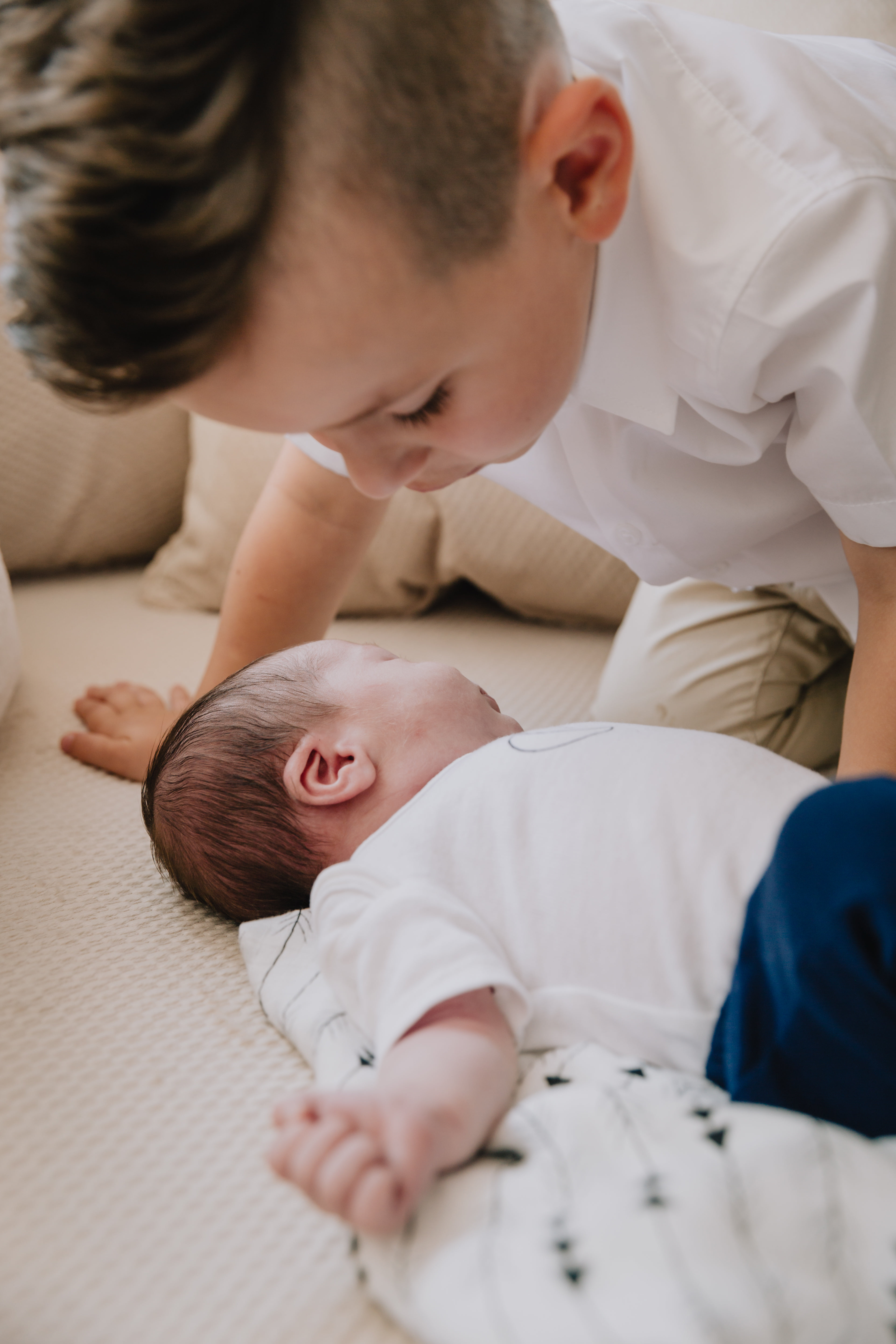 Baby Lays On A Blanket With A Child Saying Hello