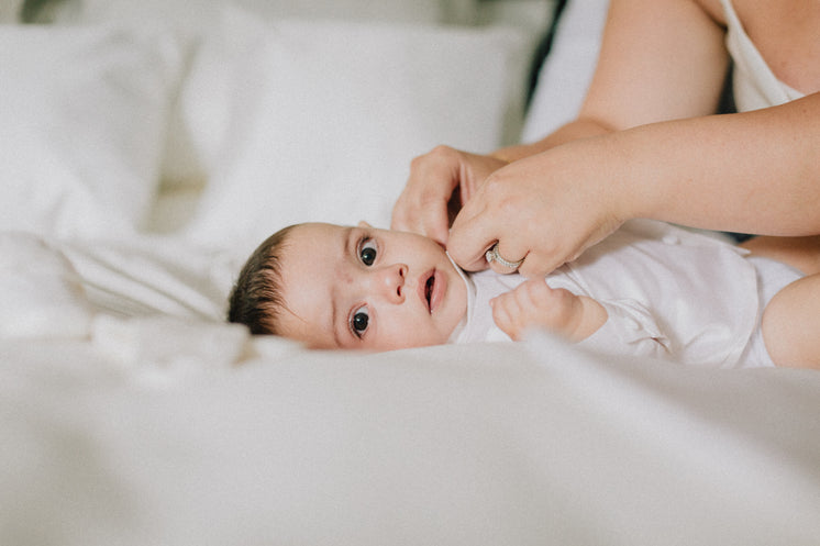 Baby Lays On White Duvet Looking At The Camera