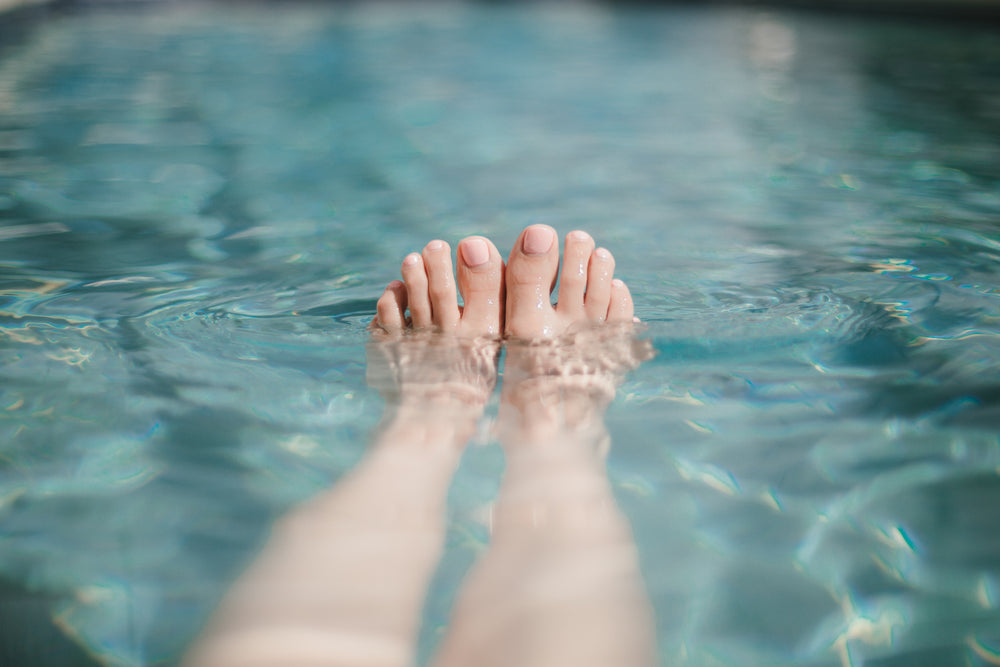 baby pink painted toes peeking out of swimming pool