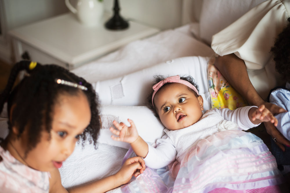 baby reaches for her sister