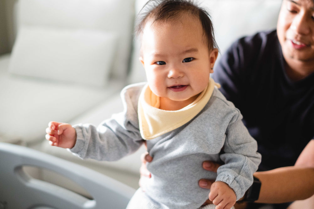 baby smiles while held by their father looking at the camera