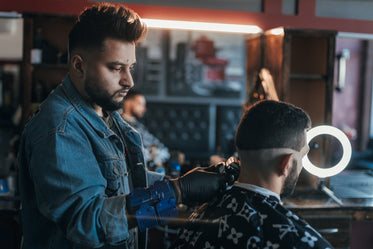 barber uses clippers to line up hair