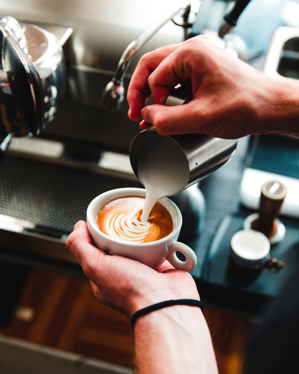 barista pours steamed milk on espresso