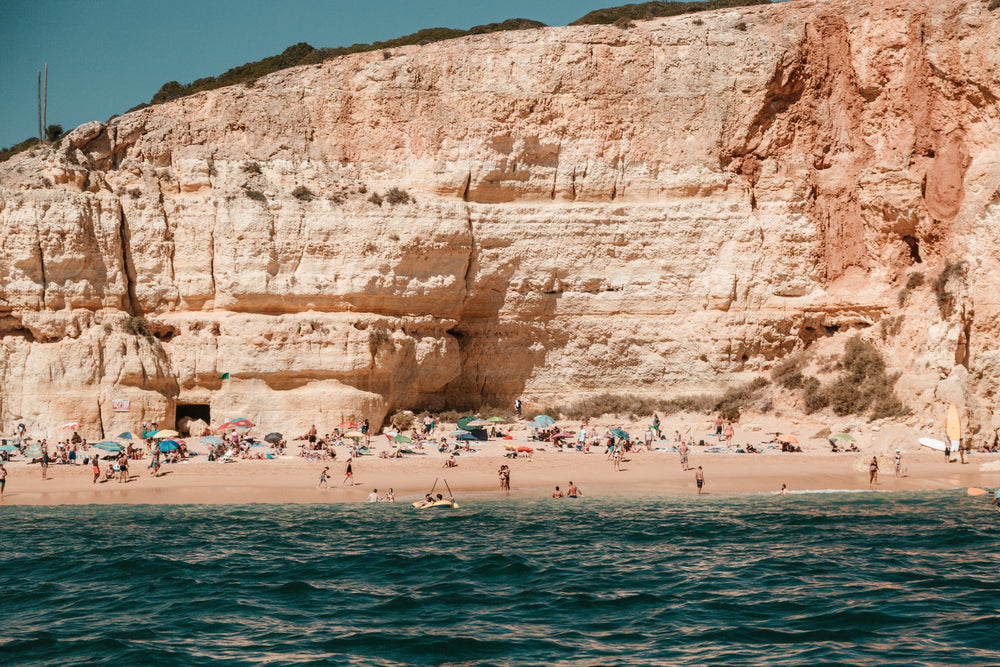 bathers on a sandy beach against a craggy cliff