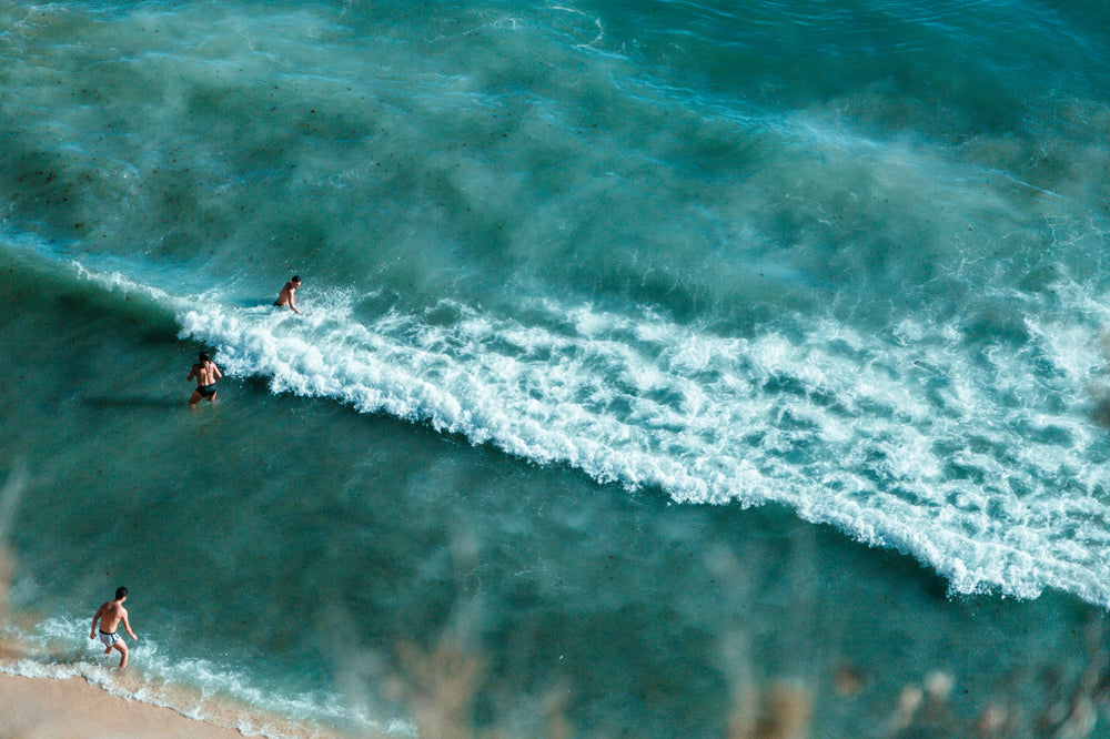 bathers wade into turquoise waters off a sandy beach