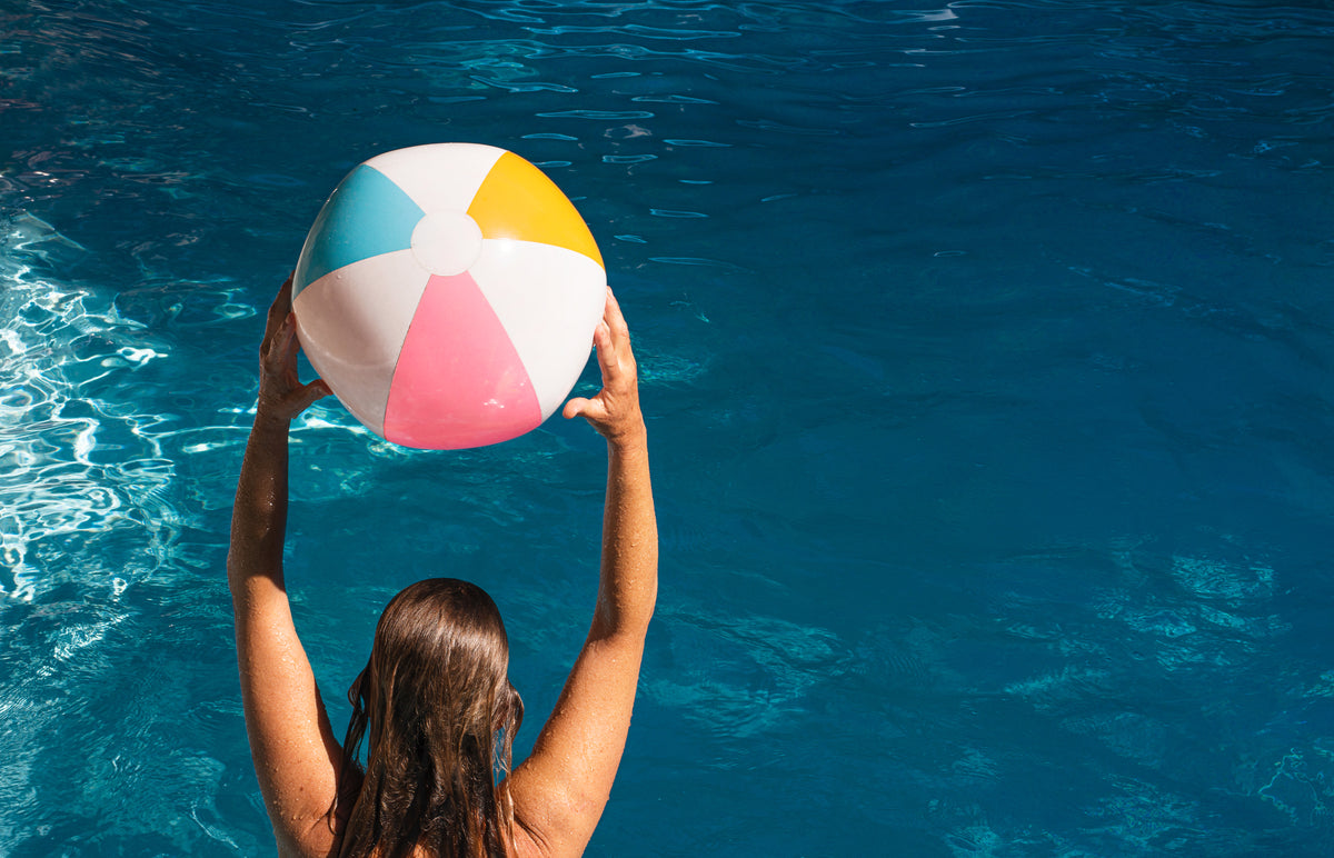 beach ball held high in swimming pool