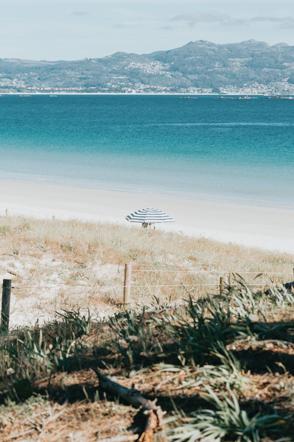 beach with aqua blue water and a single beach umbrella