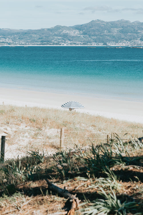 beach with aqua blue water and a single beach umbrella