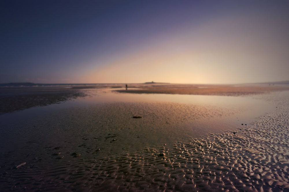 beach with shallow water with person in the distance