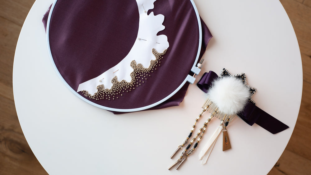 beading work on purple fabric sat on white table