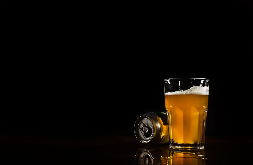 beer can and glass with spill reflection