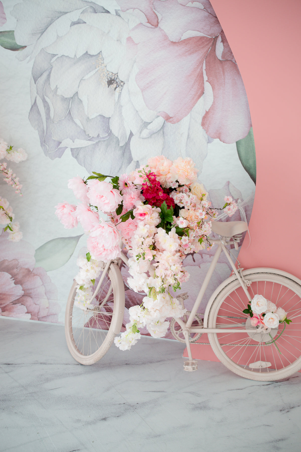 一辆挂满鲜花的自行车靠在花墙上