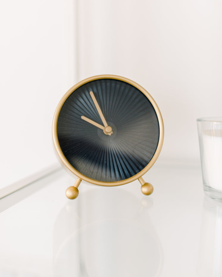 Black And Gold Clock Sits On A White Table