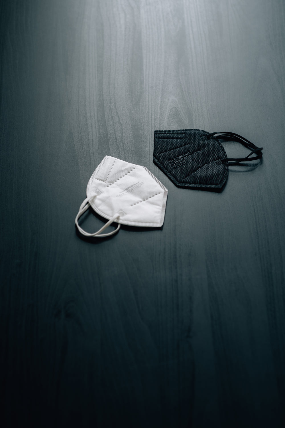 black and white face masks on a dark wooden surface