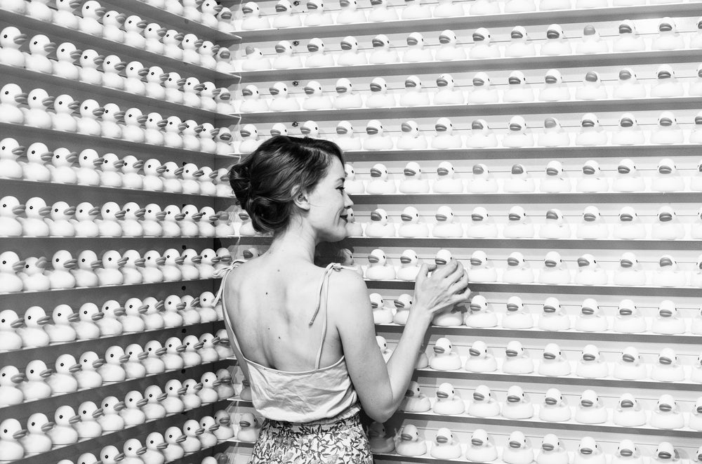 black and white image of woman admiring rubber ducks