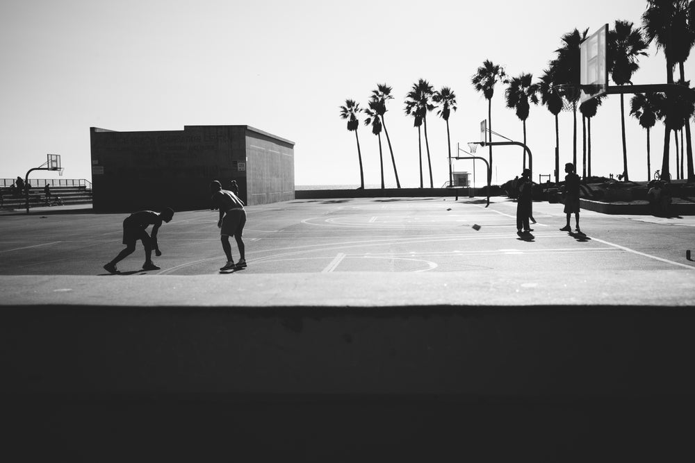 black and white people playing basketball near beach