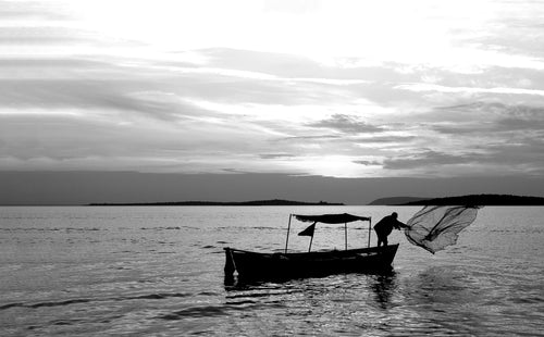 black and white photo a person throwing a fishing net