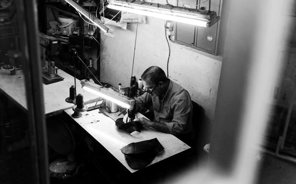 black and white photo of a person sitting by sewing machine