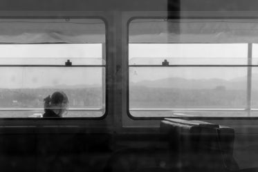 black and white photo of a person sitting in a window