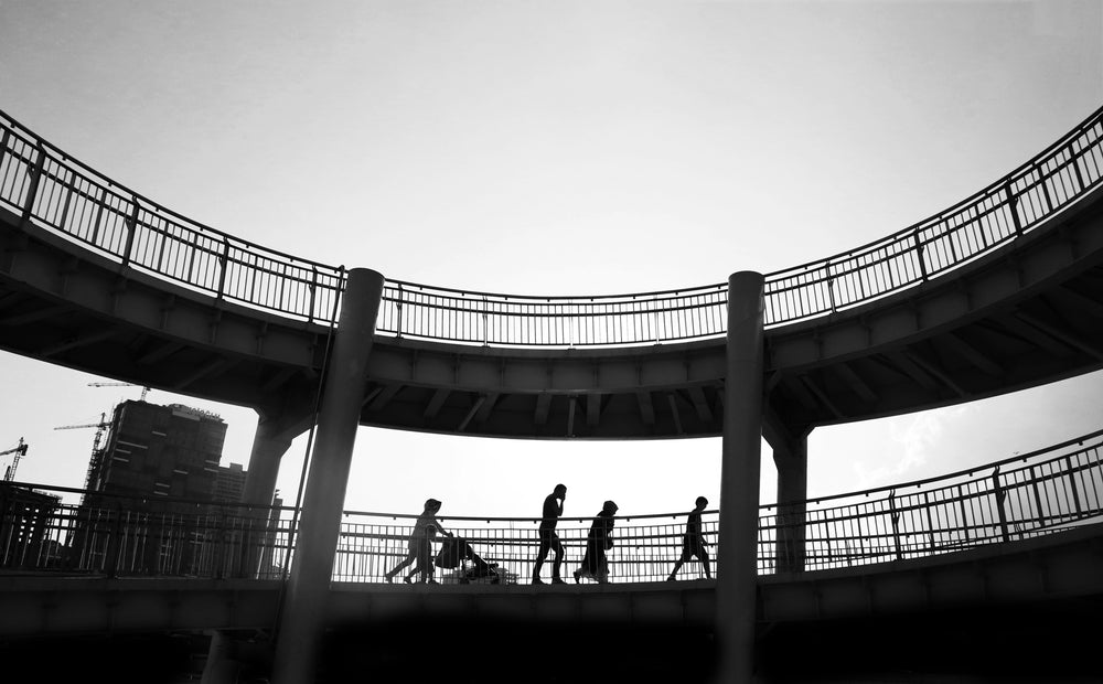 black and white photo of people walking in a bridge