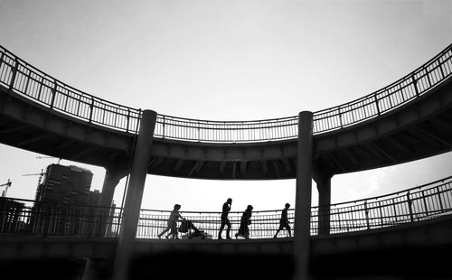 black and white photo of people walking in a bridge