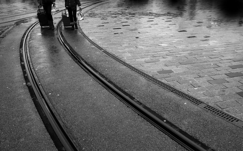 black and white photo of train lines and two peoples legs