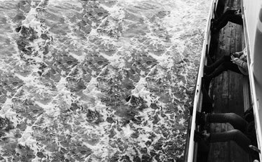 black and white photo of waves and people in a boat
