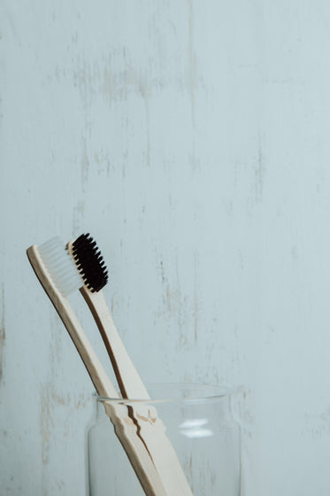 black and white wooden toothbrushes in a glass cup