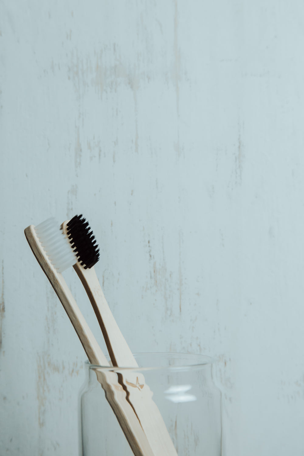 black and white wooden toothbrushes in a glass cup