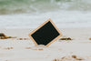 black chalkboard sticking out of a white sandy beach