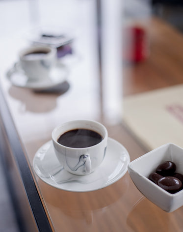 black coffee  accompanied by square bowl of olives
