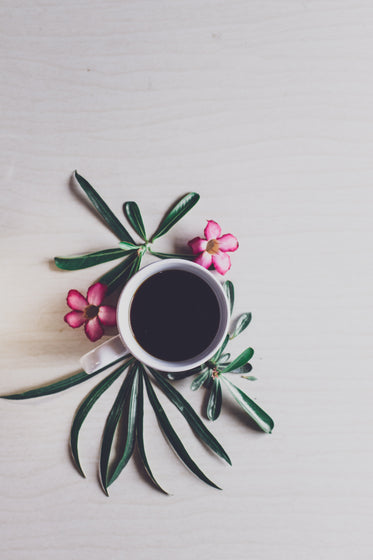 black coffee surrounded by flowers