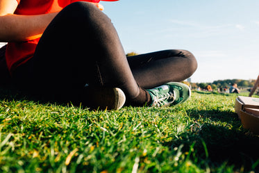 black leggings and green sneakers in a summery park