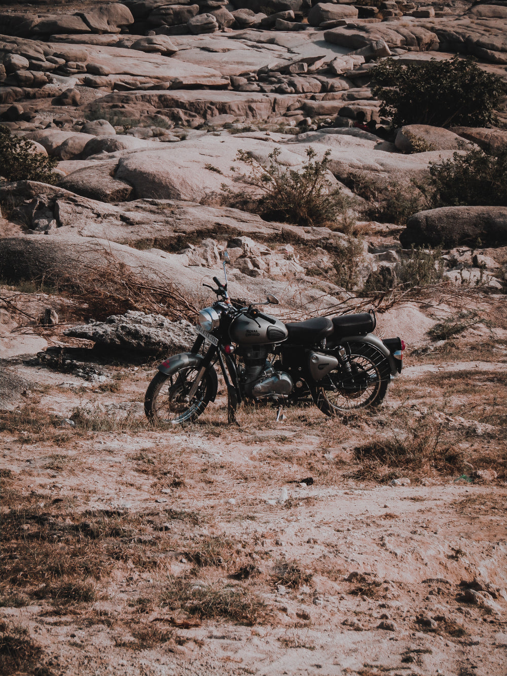 black motorcycle parked with a stone hill behind