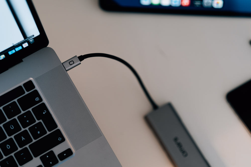 black power cord plugged into a silver laptop