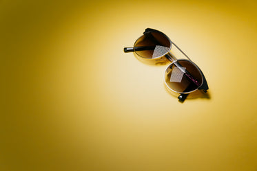 black round sunglasses on top right of yellow background